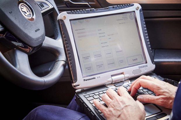 A paramedic working on a computer in the front seat of an ambulance