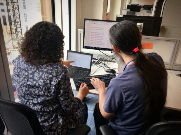 Two people looking at code on a computer