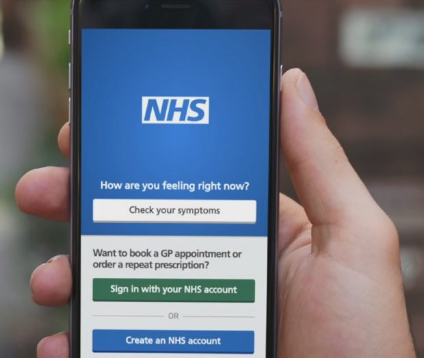 A hand holding a smart phone with the NHS app on the screen