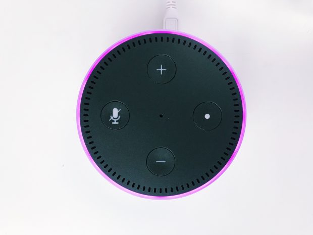 An Amazon Echo device photographed from the top down, showing a purple light indicating use
